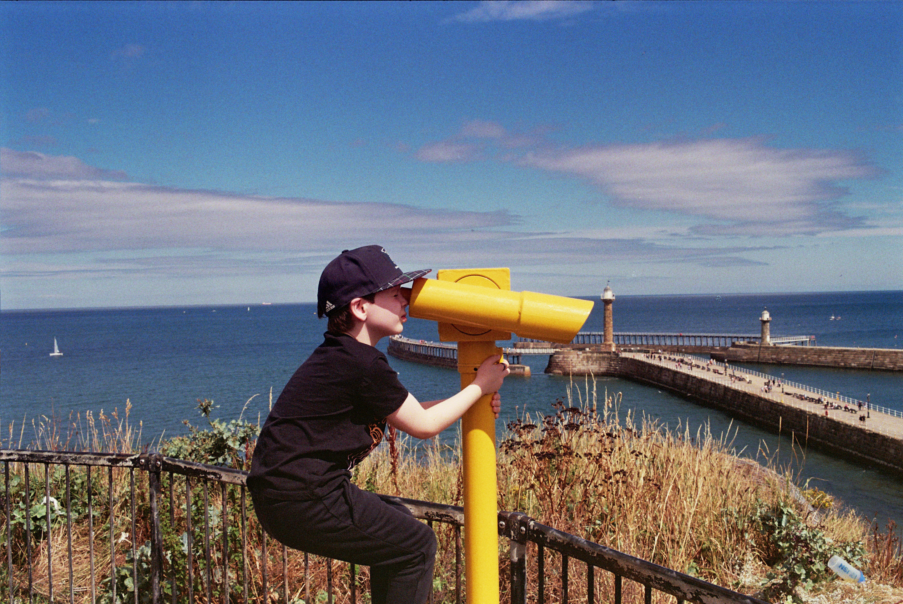 A boy looking through a telescope by the sea
